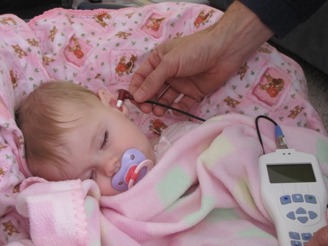 a sleeping baby girl getting a hearing screening