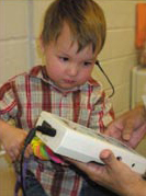 a boy playing with hearing testing equipment while getting a hearing screening