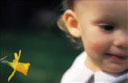 an infant sitting beside a flower