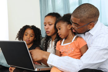 a young family gathered around a computer