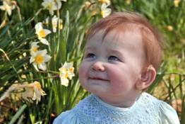 a baby girl with a hearing aid, relaxing outdoors