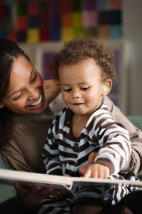 a baby reading a book to his mother