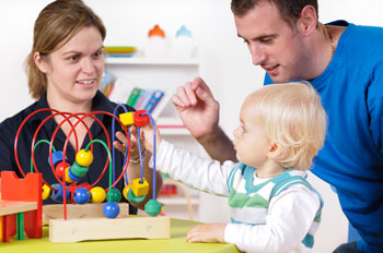 A mom and dad playing with educational toys with their baby