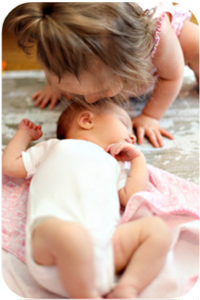 a toddler kissing a baby on the head