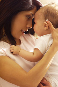 a smiling baby girl, being held by her mother