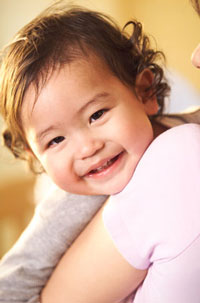 a smiling baby girl, being held by a woman