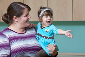 a mother holding her daughter, both smiling