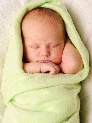 A sleeping baby, wrapped in a green blanket