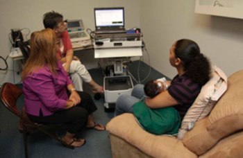 A mother holds her infant during an audiology session