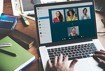 a person sitting at a computer and video conferencing with several people